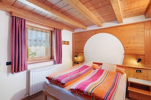 Ein Zimmer mit Holzwänden, einem Bett, einem Fenster und einem festen Kopfteil.