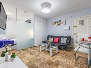 A modern living room with a glass coffee table, a black leather sofa, and a glass dining table. - Central renovated studio - Stay in Granada (Granada)