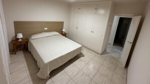 Ein Schlafzimmer mit Bett, Nachttischen, Deckenventilator und Kleiderschrank.