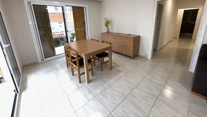Ein Zimmer mit Holztisch, Stühlen, einem Schrank und einer Glastür, die zu einem Außenbereich führt.