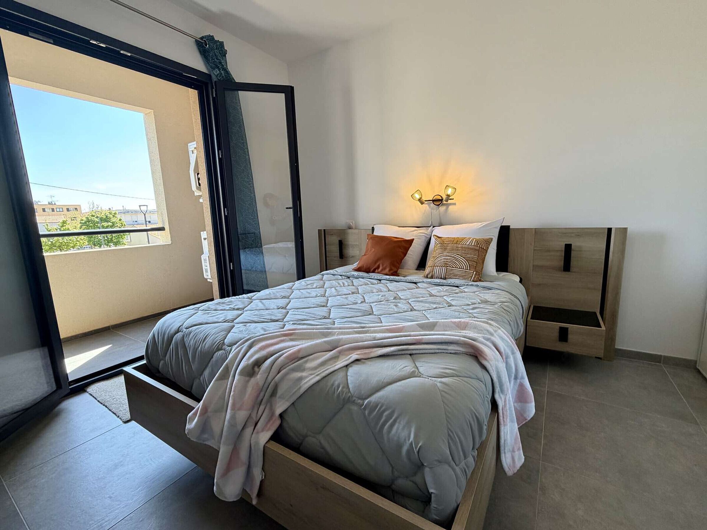 Een slaapkamer met een bed, nachtkastjes, een wandlamp en een raam met uitzicht.