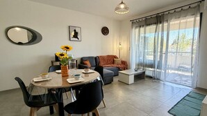 Una sala de estar moderna con comedor, un sofá, una mesa de centro y un ventanal con cortinas.