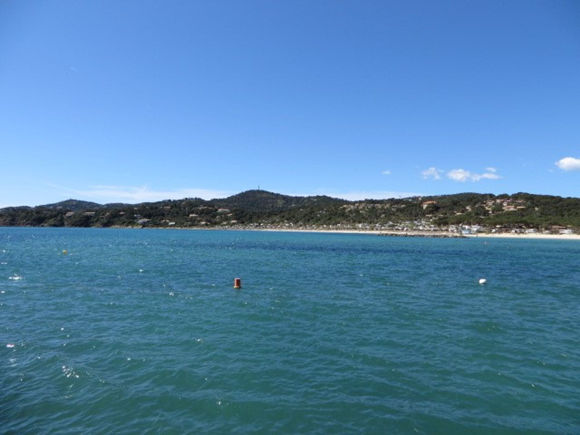 A coastal landscape with a beach and hills in the background.