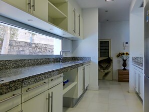 Eine Küche mit Granit Arbeitsplatten, weißen Schränken und einem Fenster mit Blick auf eine Steinmauer.