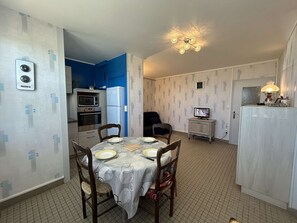 Una cocina compacta con comedor, un reloj, un televisor y una lámpara.