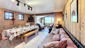 A cozy cabin interior with a dining table set, a sofa, and a television. - Apartment with panoramic view - 8 guests (La Toussuire)
