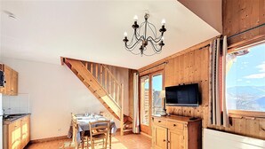 Eine Küche mit Holzausstattung, einem Esstisch für vier Personen, einer Kristallleuchtre und einem großen Fenster mit Aussicht.