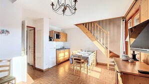Eine geräumige Küche mit Holzausstattung, ein Essbereich mit Tisch für vier Personen und eine Treppe, die in einen oberen Bereich führt.