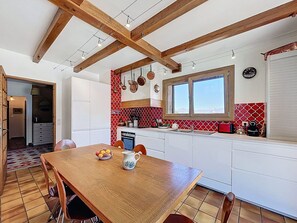 A kitchen with wooden beams, white cabinets, a red and white backsplash, and a dining area with a table and chairs. - Authentic chalet, mountain view - 15 guests (La Toussuire)