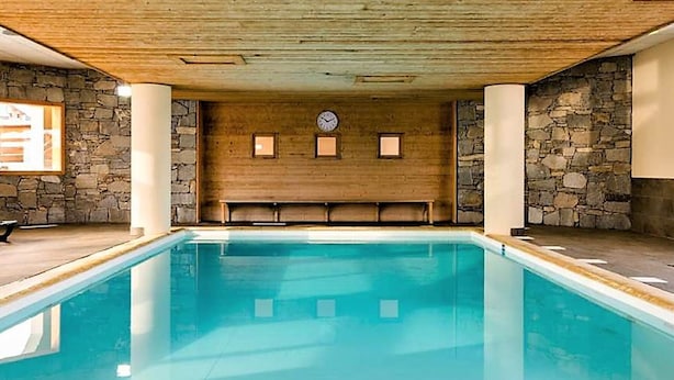Una piscina con paredes de piedra y vigas de madera en el techo.