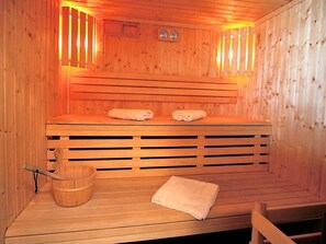Una sauna de madera con bancos, un balde de madera y toallas.