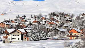 Un pueblo cubierto de nieve con casas de madera y un cielo azul despejado.