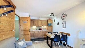 Un espacio habitable compacto con cocina, comedor y un sofá con un cojín en forma de corazón.