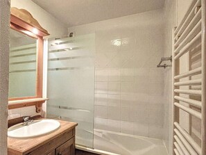 A bathroom with a wooden vanity, a mirror, a shower with a glass door, and a towel rack. - Calm apartment, balcony with view - 6 guests (La Toussuire)
