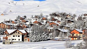 Un pueblo cubierto de nieve con casas de madera y montañas al fondo.