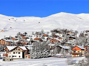 A snow-covered village with wooden houses and a mountain backdrop. - Calm apartment, balcony with view - 6 guests (La Toussuire)
