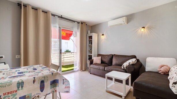 A living room with a sofa, a table, and a sliding door leading to a balcony. - Apartment 'Salou Beach' with Sea View, Wi-Fi, and Air Conditioning (Salou)