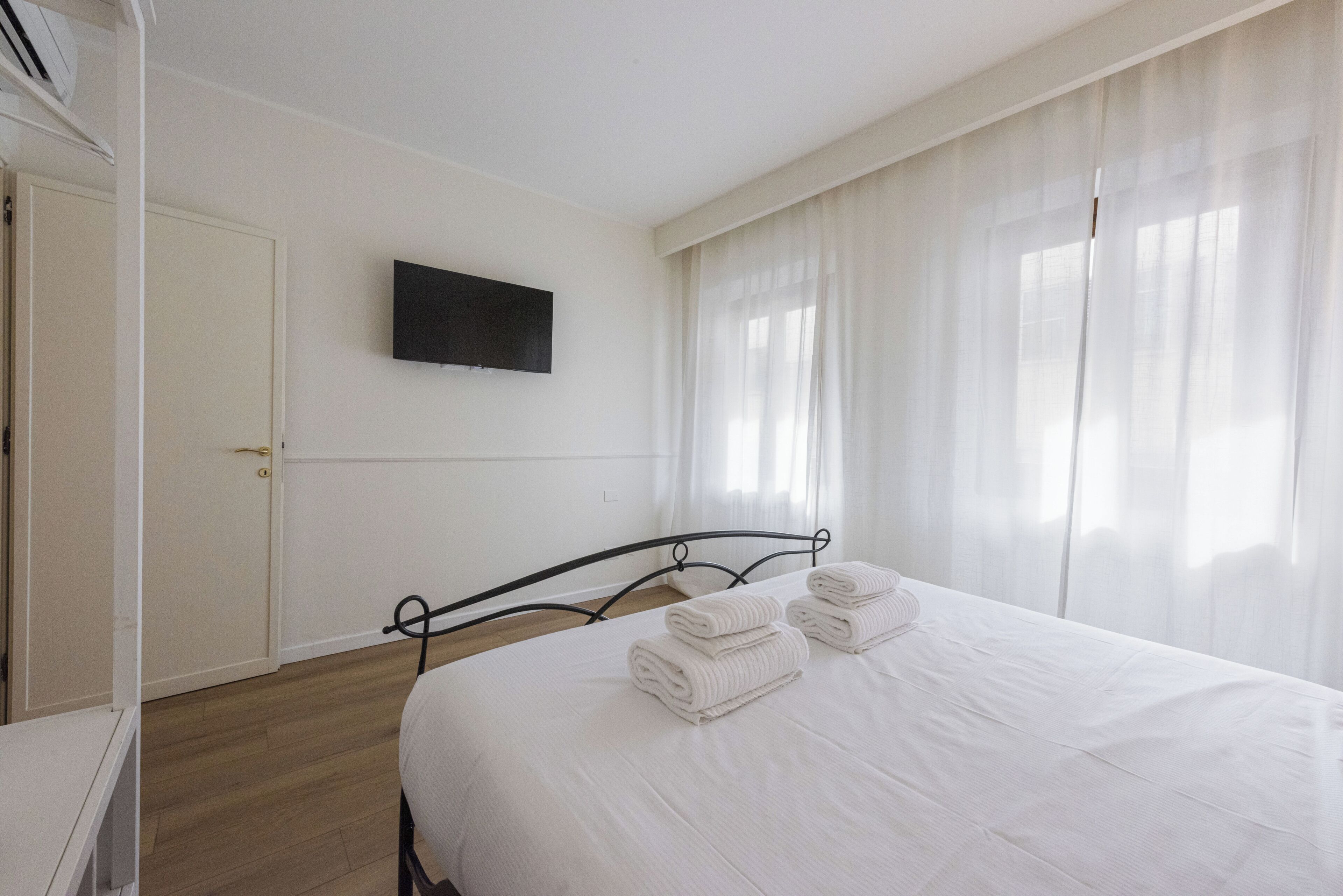A bedroom with a bed, a television on the wall, and a door.