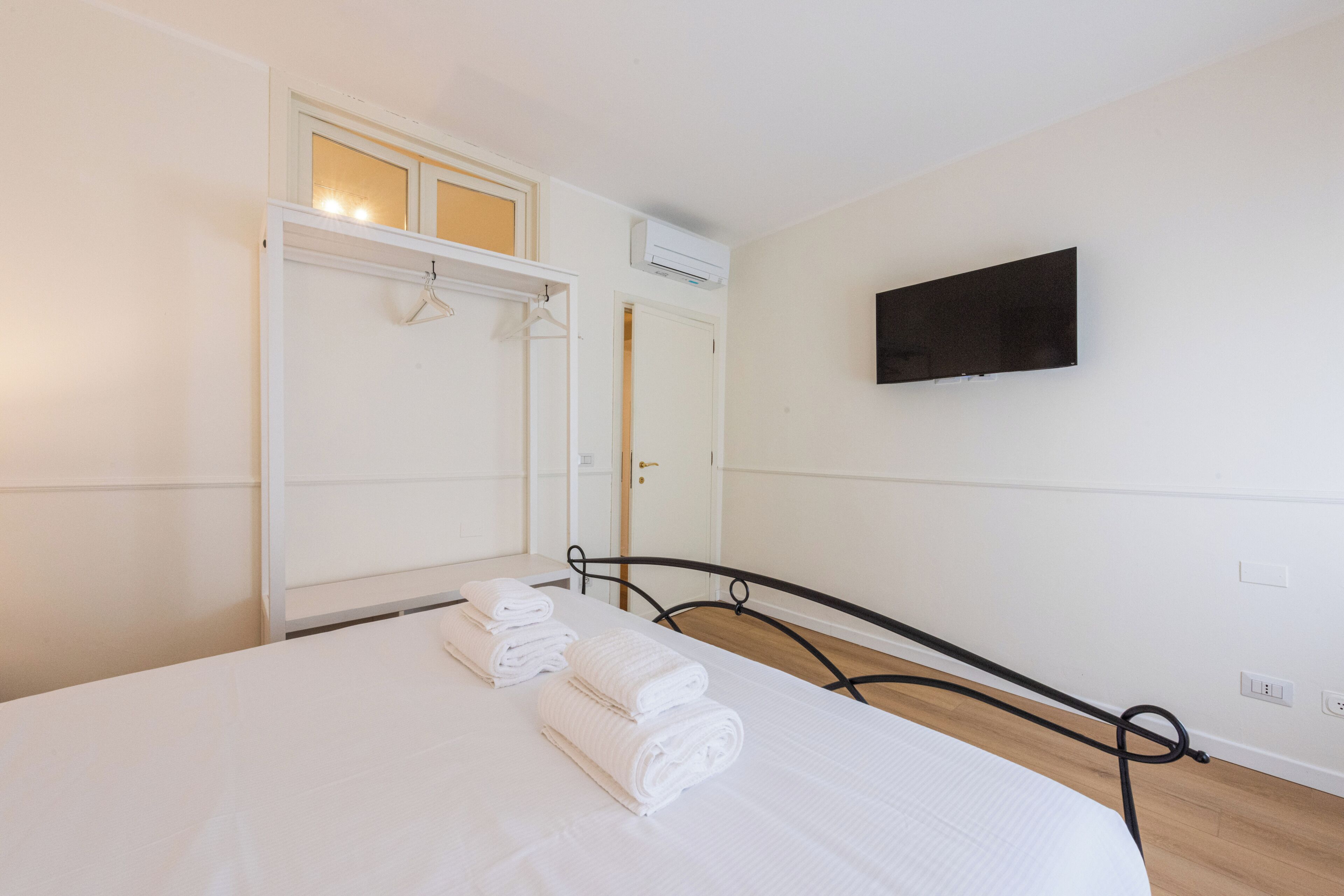 A bedroom with a bed, a wardrobe, a television, and a hanging light fixture.