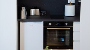 Una cocina compacta con horno empotrado, cafetera y hervidor sobre la encimera.