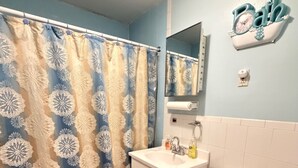 A bathroom with a shower curtain, sink, toilet, and a mirror. - Move-In Ready 2BR Apartment – Clean, Cozy & Conveniently Located (Brooklyn)