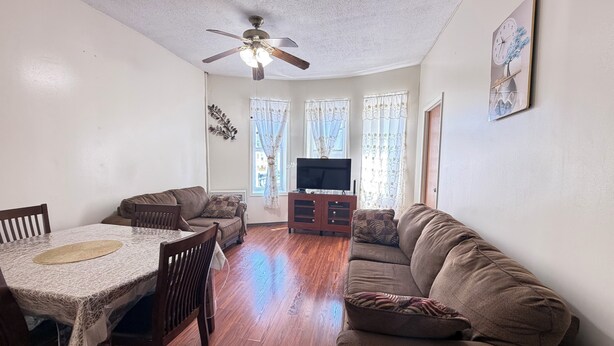 A living room with a dining table, sofas, a TV, and a ceiling fan. - Move-In Ready 2BR Apartment – Clean, Cozy & Conveniently Located (Brooklyn)