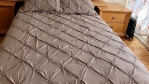 A bed with a quilted cover, a wooden nightstand, and a small drawer. - Move-In Ready 2BR Apartment – Clean, Cozy & Conveniently Located (Brooklyn)