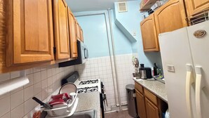A kitchen with wooden cabinets, a gas stove, a sink, and a refrigerator. - Move-In Ready 2BR Apartment – Clean, Cozy & Conveniently Located (Brooklyn)