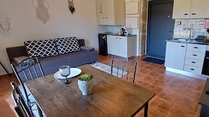 A compact kitchen with a dining area, a sofa, and a small table with a plant. - Retreat in Beira Interior, private outdoor jacuzzi, AC and breakfast!!! (Telhado)