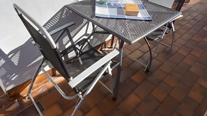A metal outdoor table with a checkered tablecloth and a book on it.