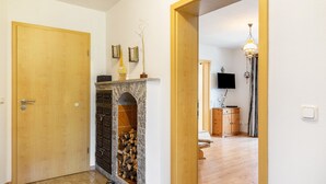 Ein Flur mit einer Holztür, einem Kamin mit steinernen Rundbögen und einem Holzschrank.