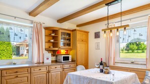 Eine Küche mit Holzausstattung, einer Mikrowelle und einem Esstisch mit weißer Tischdecke.