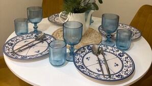 Ett runt matbord med blå- och vitmönstrade tallrikar, blått glas och en vit vas med vita blommor och gröna blad.