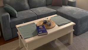 Ett vardagsrum med en soffa, ett soffbord med en bok och ett ljus, och en lampa.