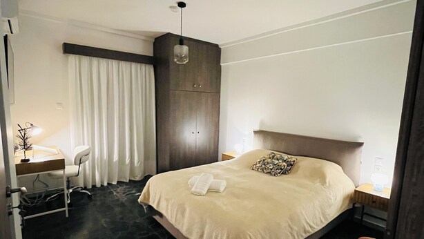 Ein Hotelzimmer mit einem Bett, einem Schreibtisch, einem Stuhl, einem Kleiderschrank und einer Pendelleuchte.