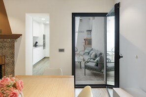 Una habitación con una mesa de comedor, una silla, un sofá y una puerta corrediza de vidrio que da a una zona de cocina.