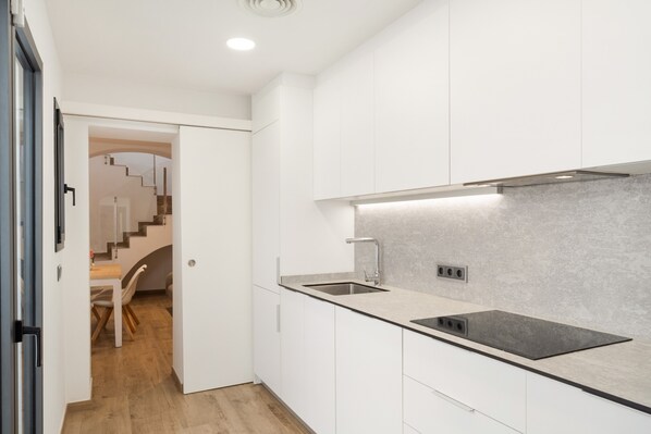 A modern kitchen with white cabinetry, a stainless steel sink, and a built-in stove.