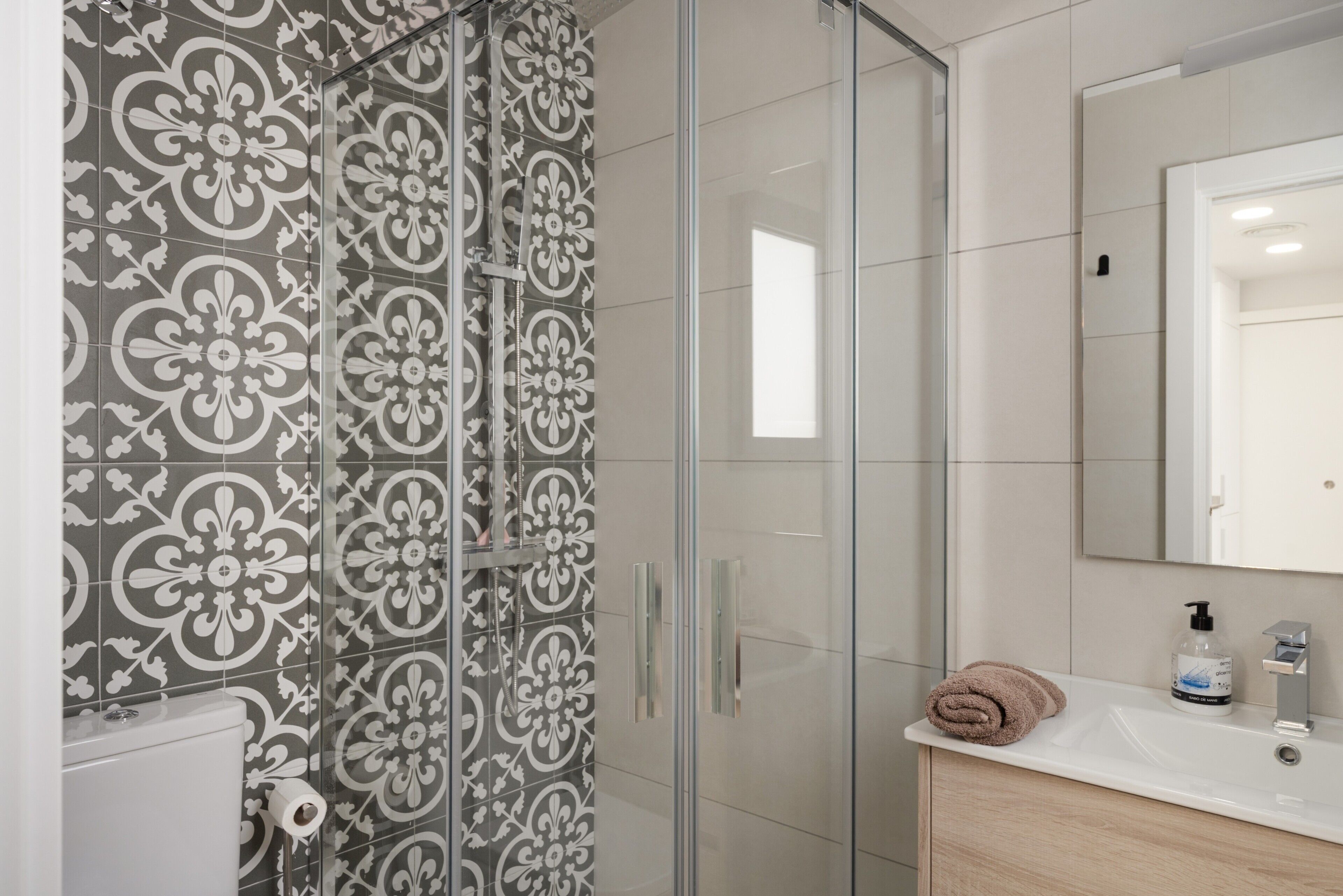A bathroom with a shower, toilet, sink, and mirror.