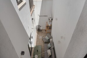 A narrow courtyard with a sofa, chairs, and a small table.