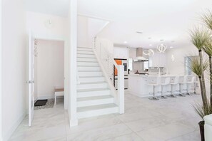 A modern interior with a staircase, a kitchen area, and a bar with stools. - The Salty Palm l Pool l Walk to DNTN (St. Augustine)