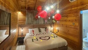 Un dormitorio de cabaña de madera con cama, mesitas de noche y un ventilador de techo.