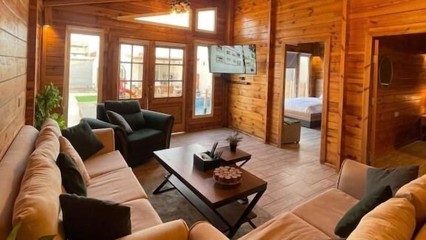 Interior de una cabaña de madera con un sofá, una mesa de centro y un televisor.