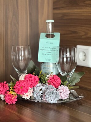 En bricka med två tomma vinglas, en flaska vatten och en liten blomsterbukett på ett träbord.