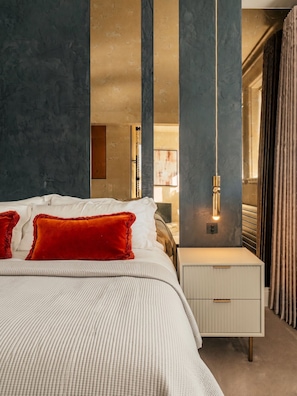 Een slaapkamer met een bed, een nachtkastje en een hanglamp.