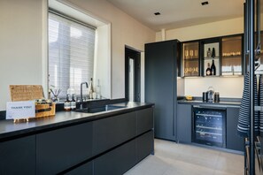 Una cucina moderna con una grande isola, un frigorifero per vini integrato e una finestra con persiane.