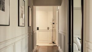 A hallway with framed pictures on the walls, a door leading to a room, and a wooden floor. - The Luxury Harrogate Penthouse (North Yorkshire)