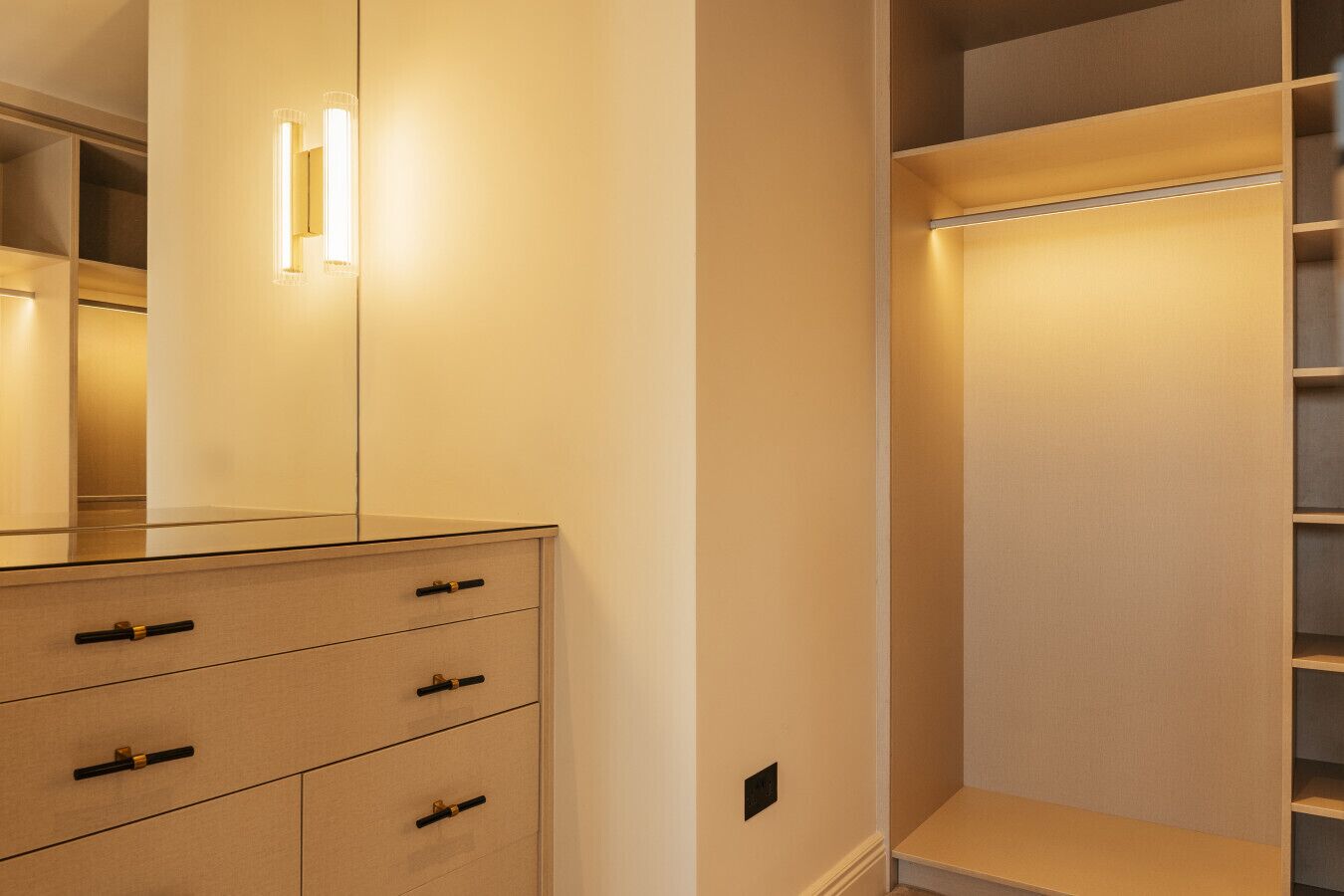 Un dressing avec éclairage intégré, une porte miroir et de nombreux tiroirs de rangement.