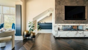 A modern living room with a fireplace, a dining area with a table and chairs, and a kitchen in the background. - The Luxury Harrogate Penthouse (North Yorkshire)