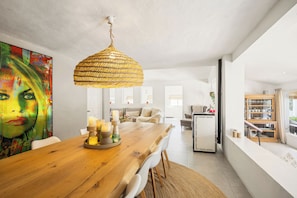 A modern dining area with a wooden table, white chairs, a hanging woven light fixture, and a colorful abstract painting on the wall. - Luxury spacious detached villa with private pool, large terrace and 7 bedrooms! (Gata de Gorgos)