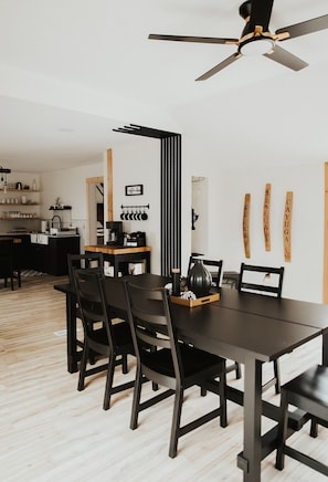 Un comedor moderno con una mesa de madera oscura, sillas negras y un ventilador de techo.